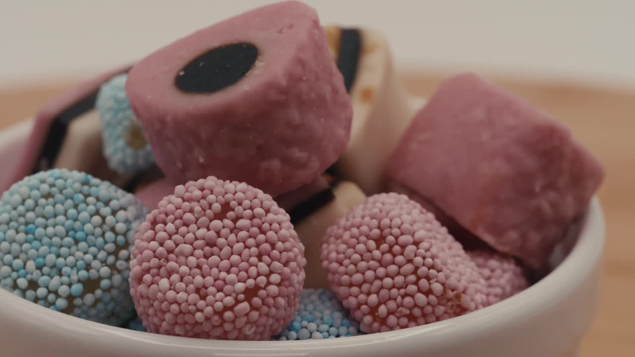特写慢动作镜头显示了一堆糖果在一个碗在模糊的背景视频下载