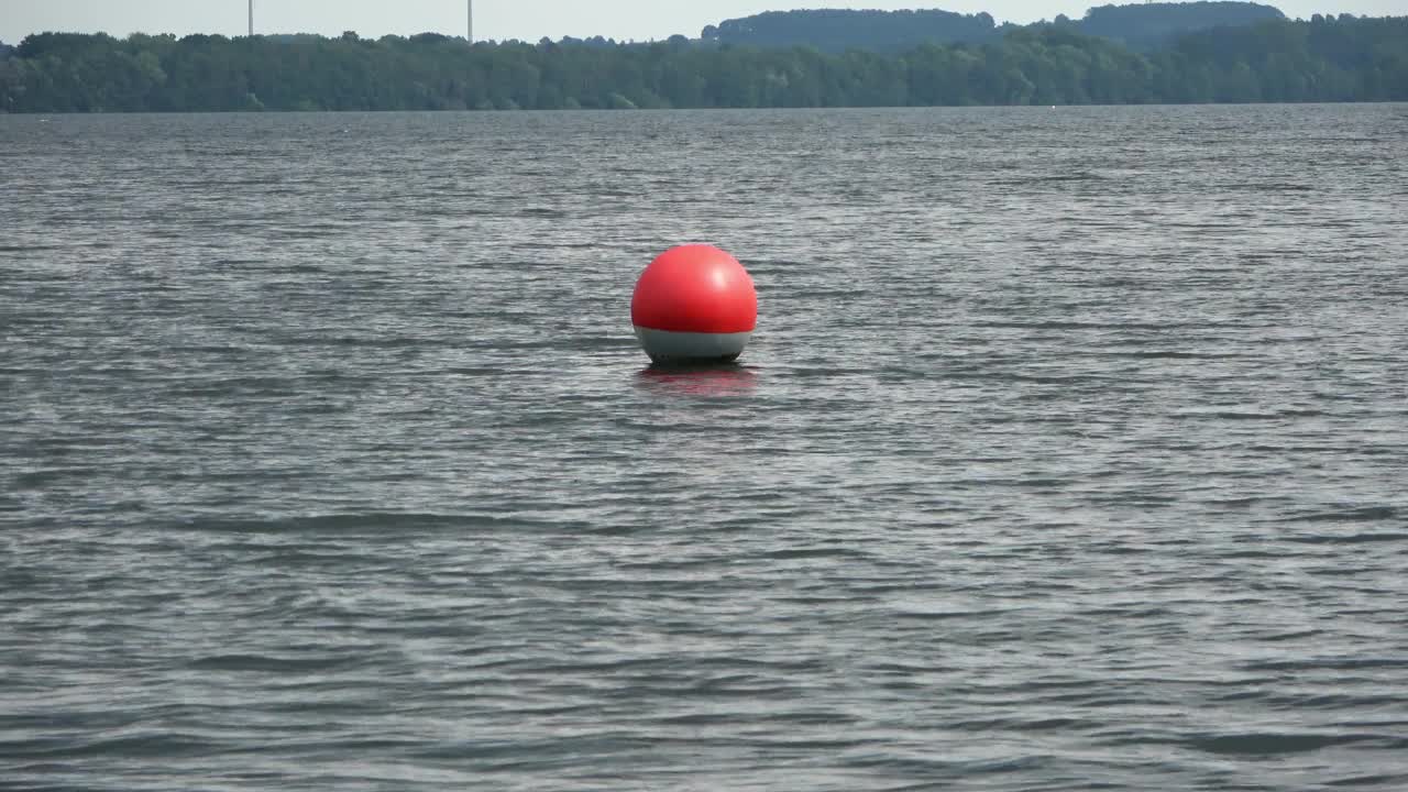 一个红色的浮标在强风中漂在湖面上。视频下载