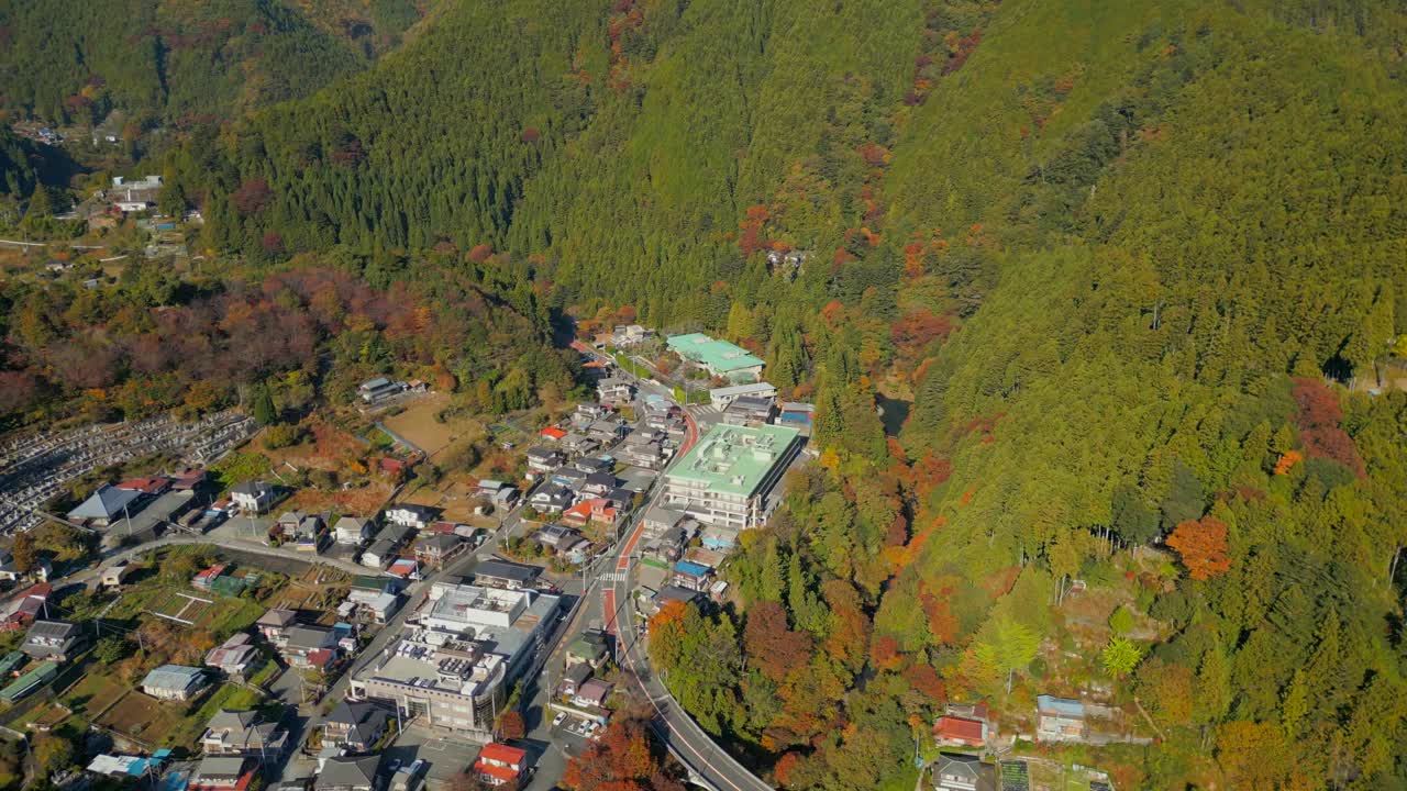 无人机在奥多摩地区上空飞行，显示山谷中的城市和附近山上的森林视频下载