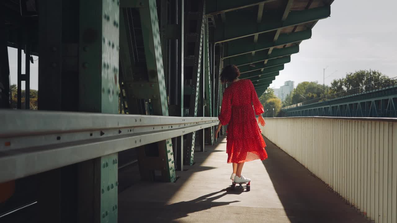 在城市的老火车桥上，穿着红色衣服的女人在玩滑板，女性滑板的城市背景视频素材