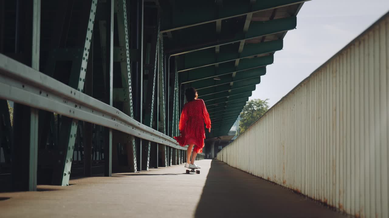 在城市的老火车桥上，穿着红色衣服的女人在玩滑板，女性滑板的城市背景视频素材