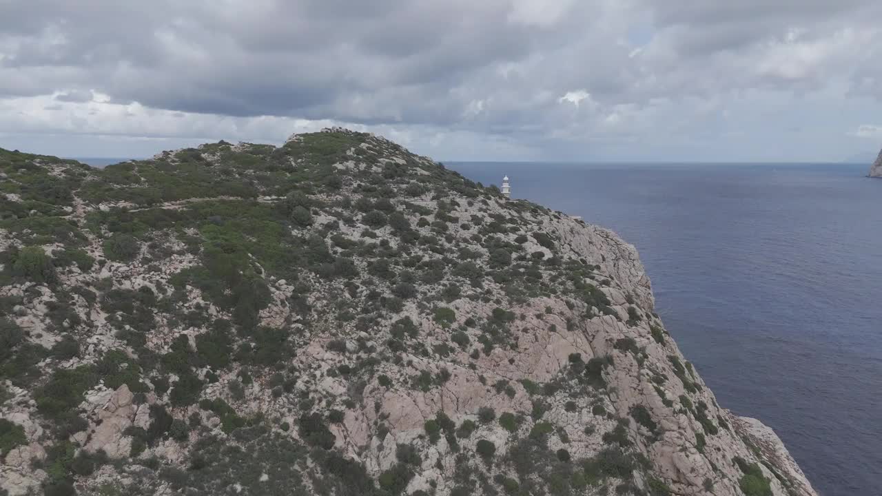 西班牙马略卡岛海岸悬崖的无人机镜头，背景是一座废弃的灯塔视频素材