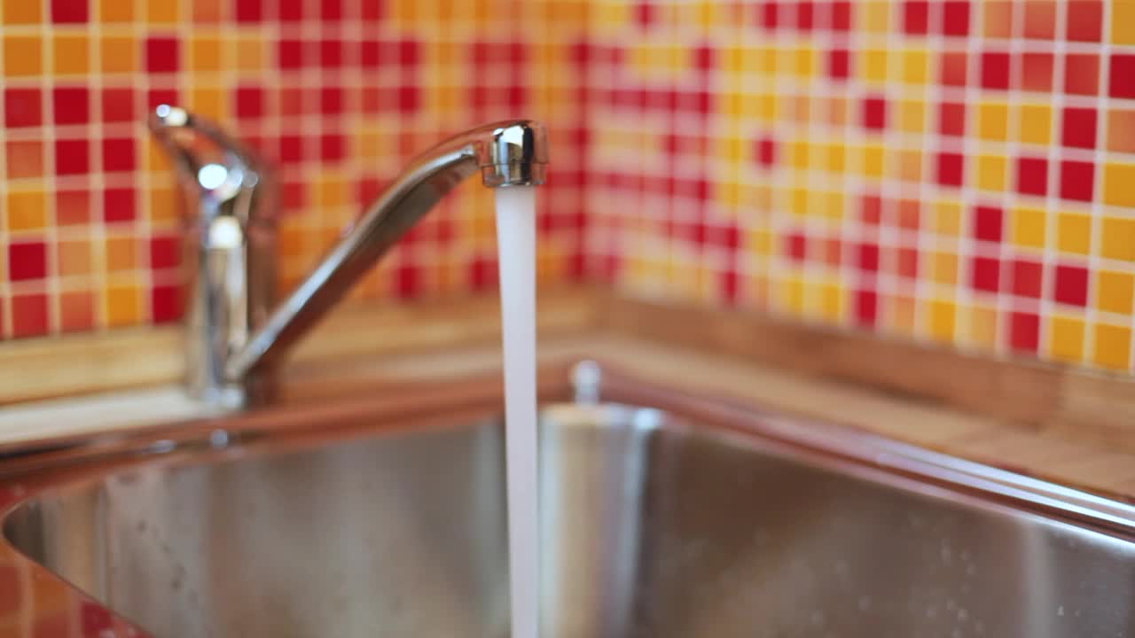 用厨房水龙头里的水装满杯子视频素材