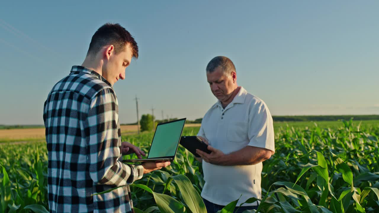 两个农民在田里工作，使用笔记本电脑和平板电脑。农业技术视频下载