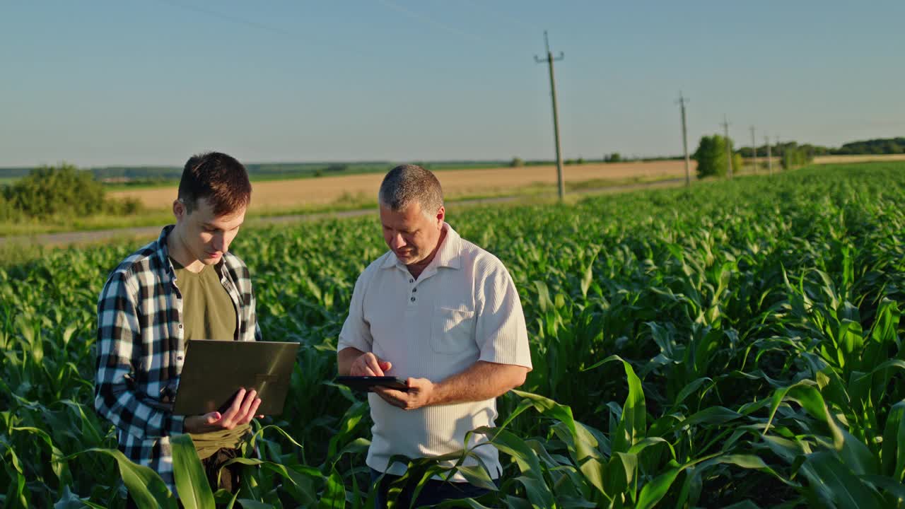 两个农民在田里劳作，使用笔记本电脑和平板电脑。农业技术视频下载