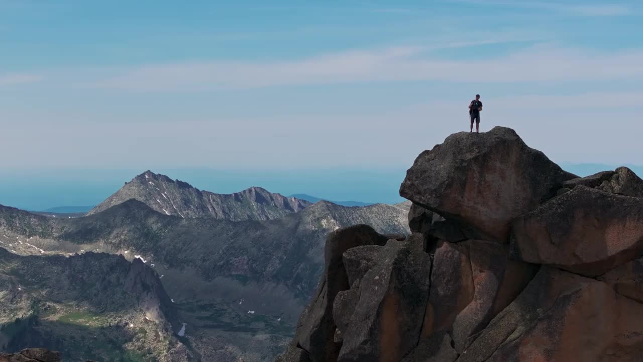 一个年轻人在山顶胜利地举起双臂视频素材