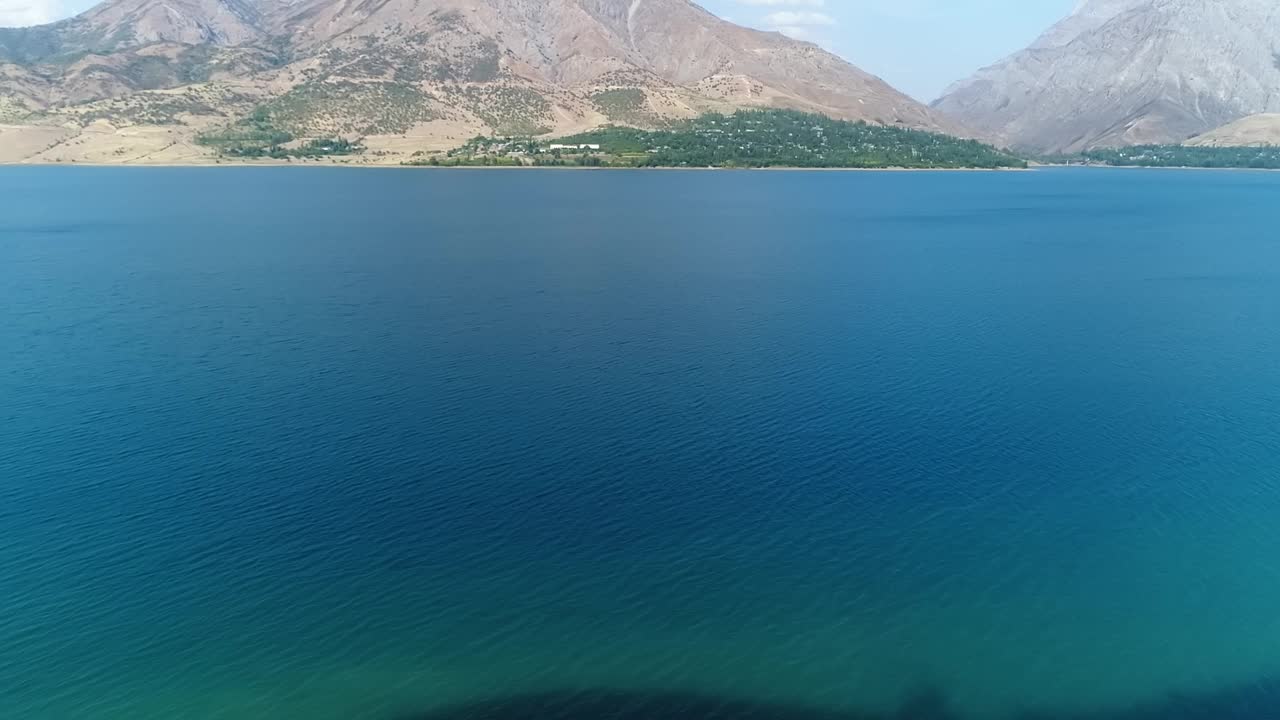 一架无人驾驶飞机飞过一个蓝色的山湖。阳光明媚的夏日视频素材