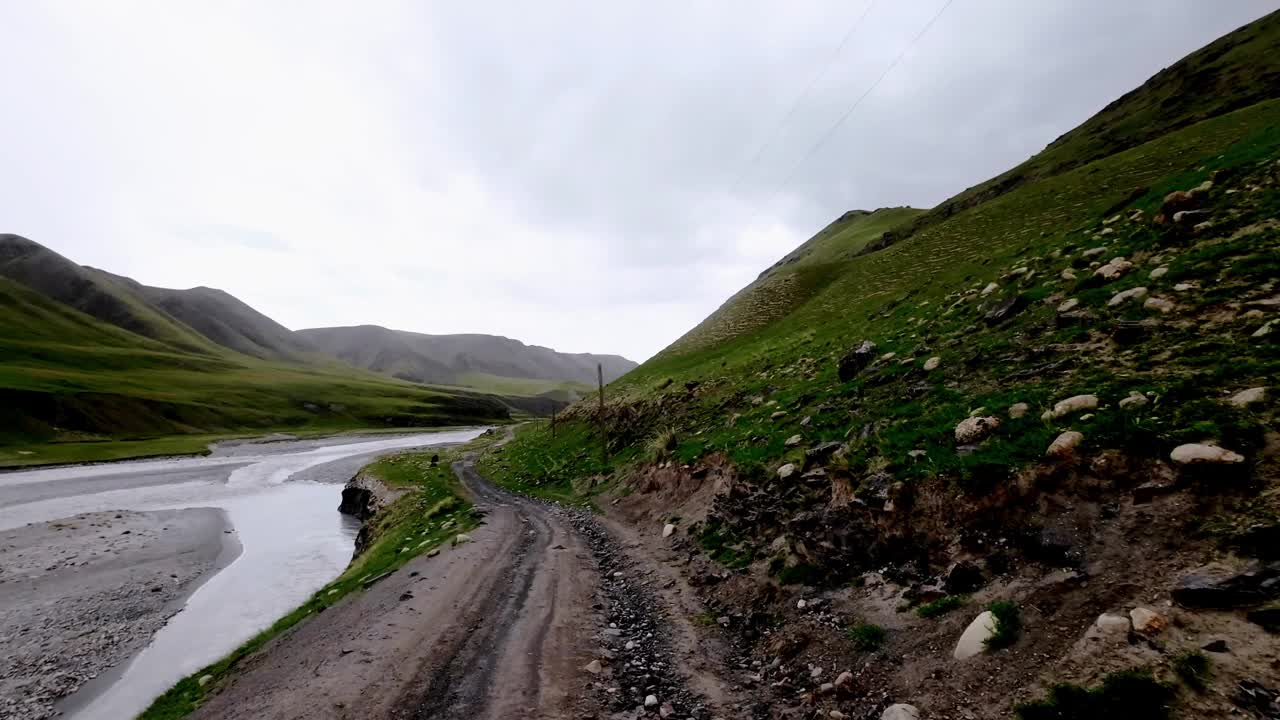 雨前灰蒙蒙的天空下，沿着山岸边的土路和石路行走视频素材