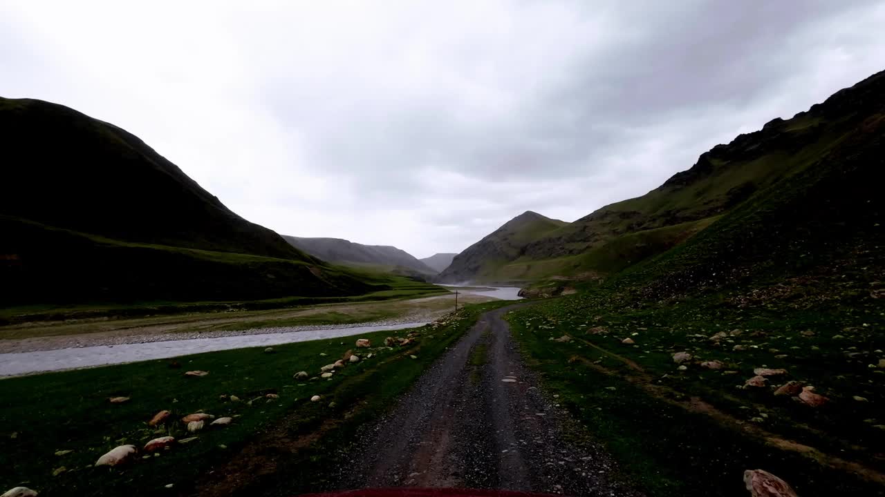 阴天下着雨，沿着山岸边的岩石和泥土小路行进视频素材