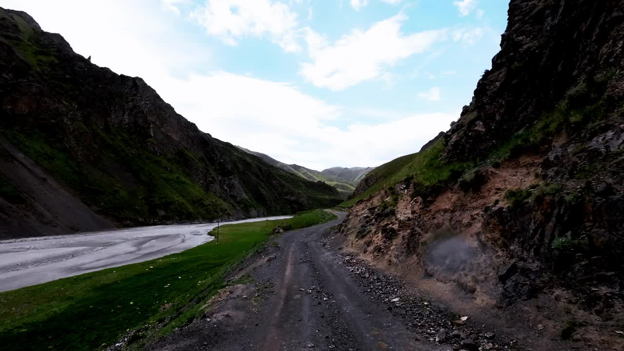 雨前多云的天空下，沿着山岸边的土石小道行进视频素材