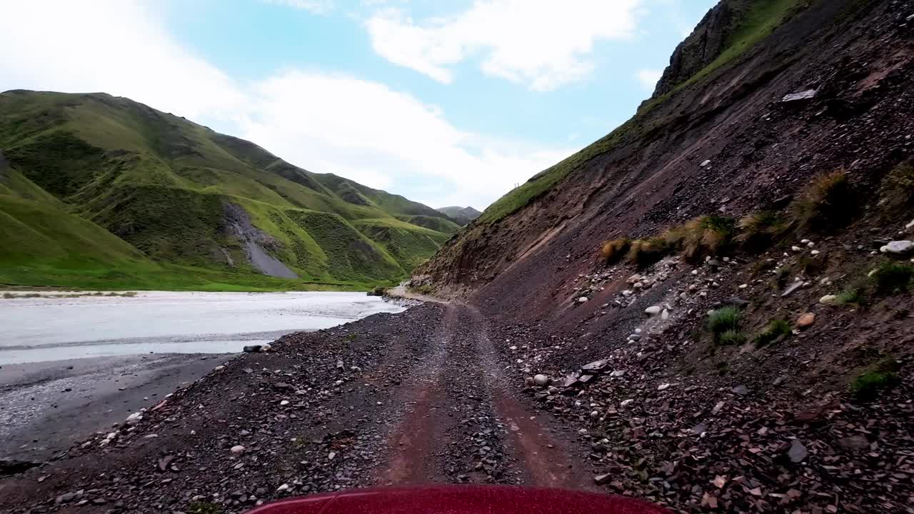 在河流和山坡之间狭窄蜿蜒的道路上行驶视频素材