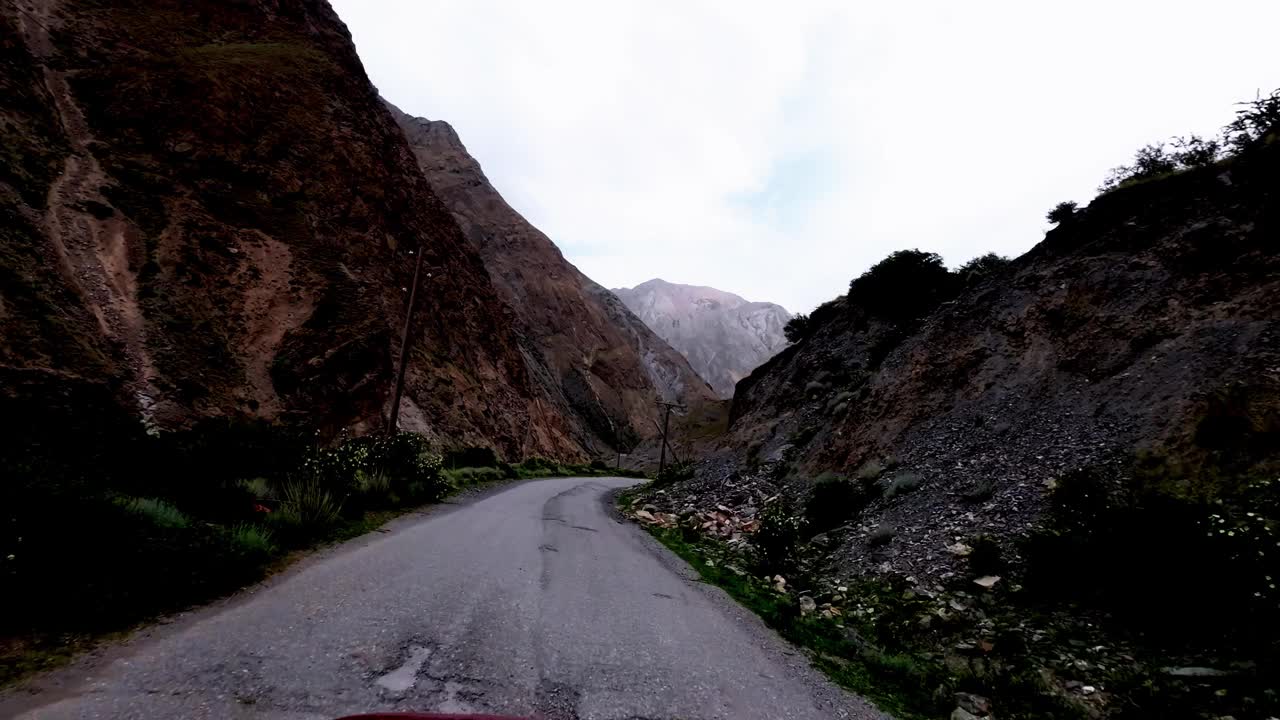 沿着古老的柏油路，沿着迷人的峡谷，在强烈的天空下行驶视频素材