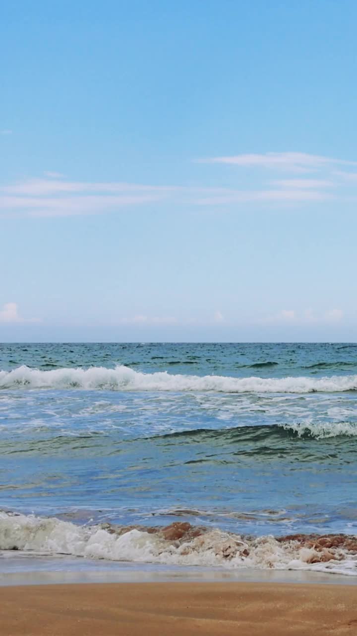 海浪翻滚到沙滩上的放松镜头。天空湛蓝清澈，点缀着缕缕白云视频素材