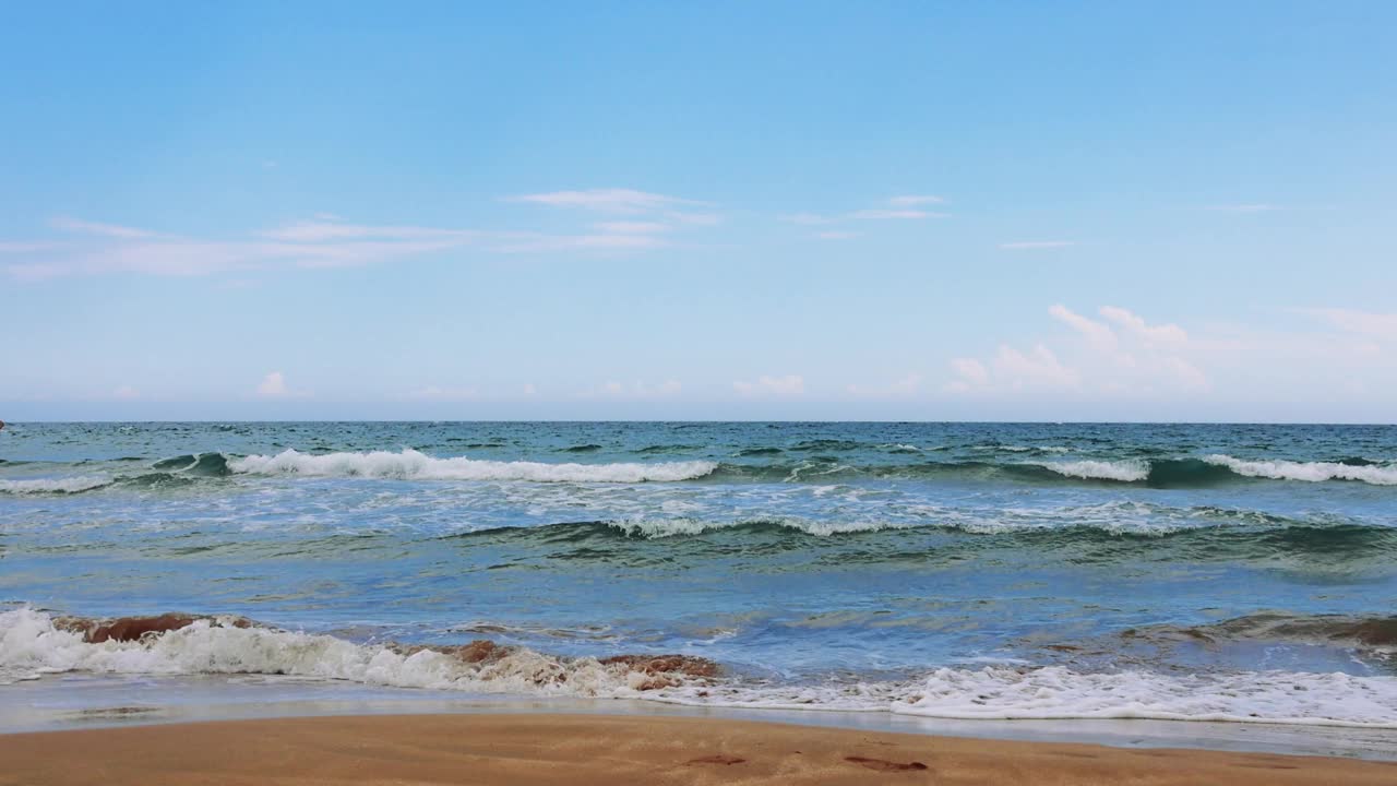 海浪翻滚到沙滩上的放松镜头。天空湛蓝清澈，点缀着缕缕白云视频素材