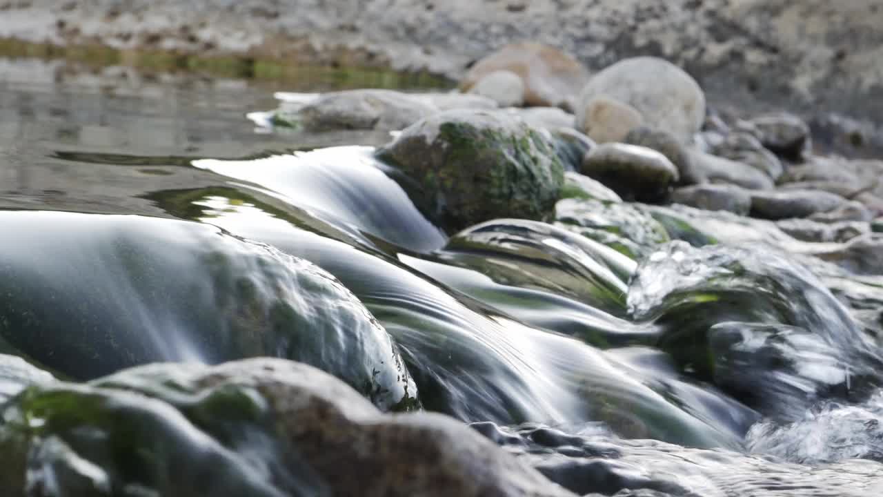 在河流的天然水池中，水在岩石之间流动的特写镜头。自然景观资源视频素材