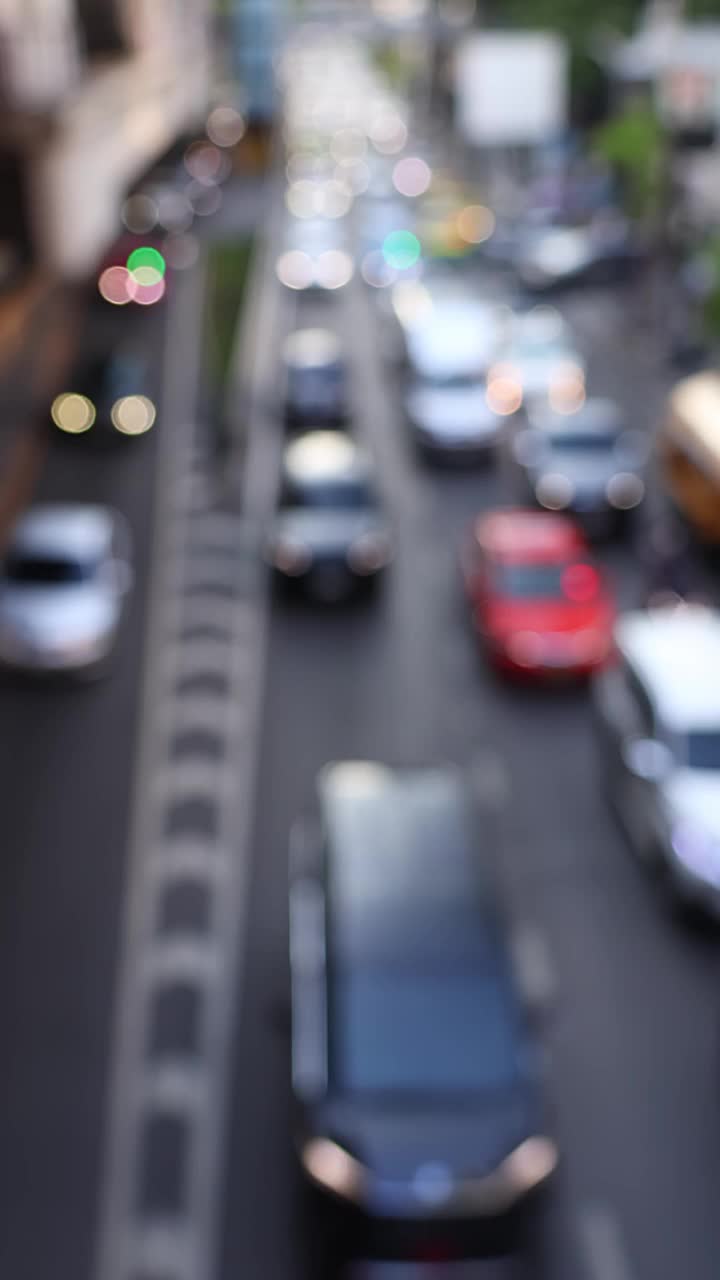 泰国曼谷Silom区Chong Nonsi BTS轻轨站附近的道路交通。汽车散景和模糊的交通灯。垂直视频。视频素材