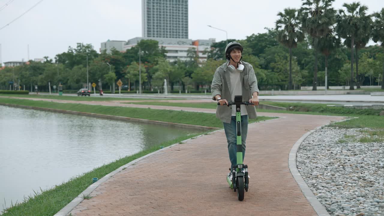 年轻的亚洲男子在市区驾驶电动滑板车，绿色能源，零碳，拯救地球的概念。视频素材