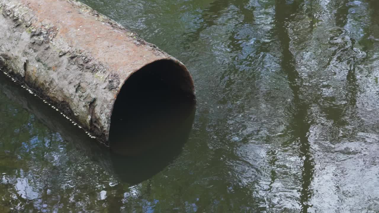 将废物排入池塘的陈旧生锈的下水管道。视频素材