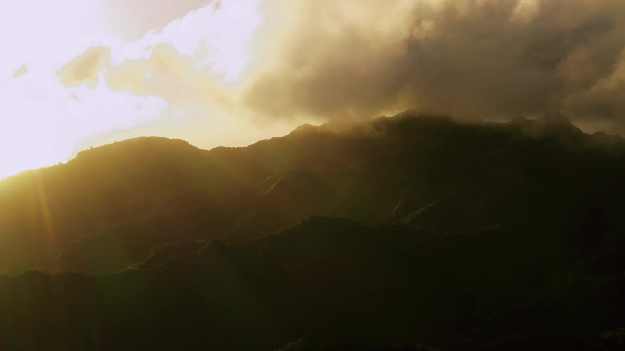 金色的云在一个热带岛屿的山顶上静静地移动。视频下载