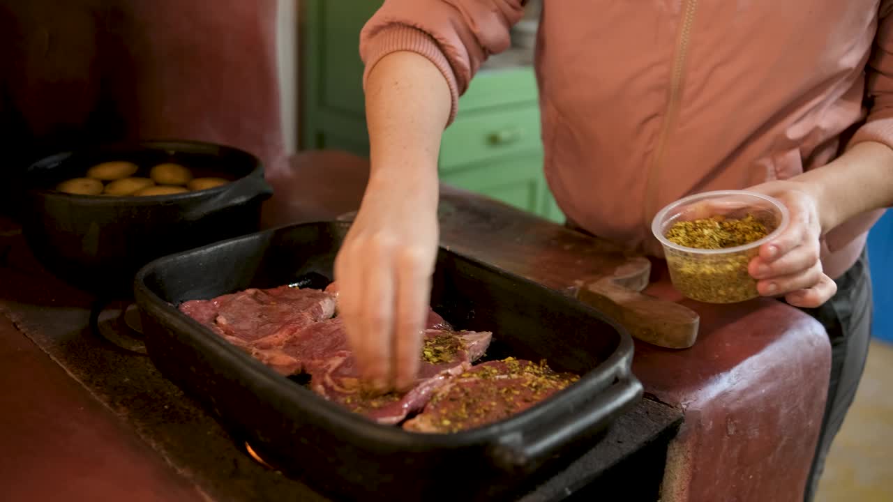 妇女在柴火烤炉里给肉片调味视频下载