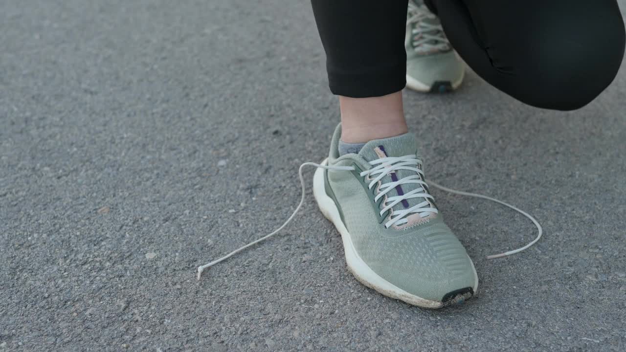 一位年轻女子在跑步前正在系鞋带视频素材