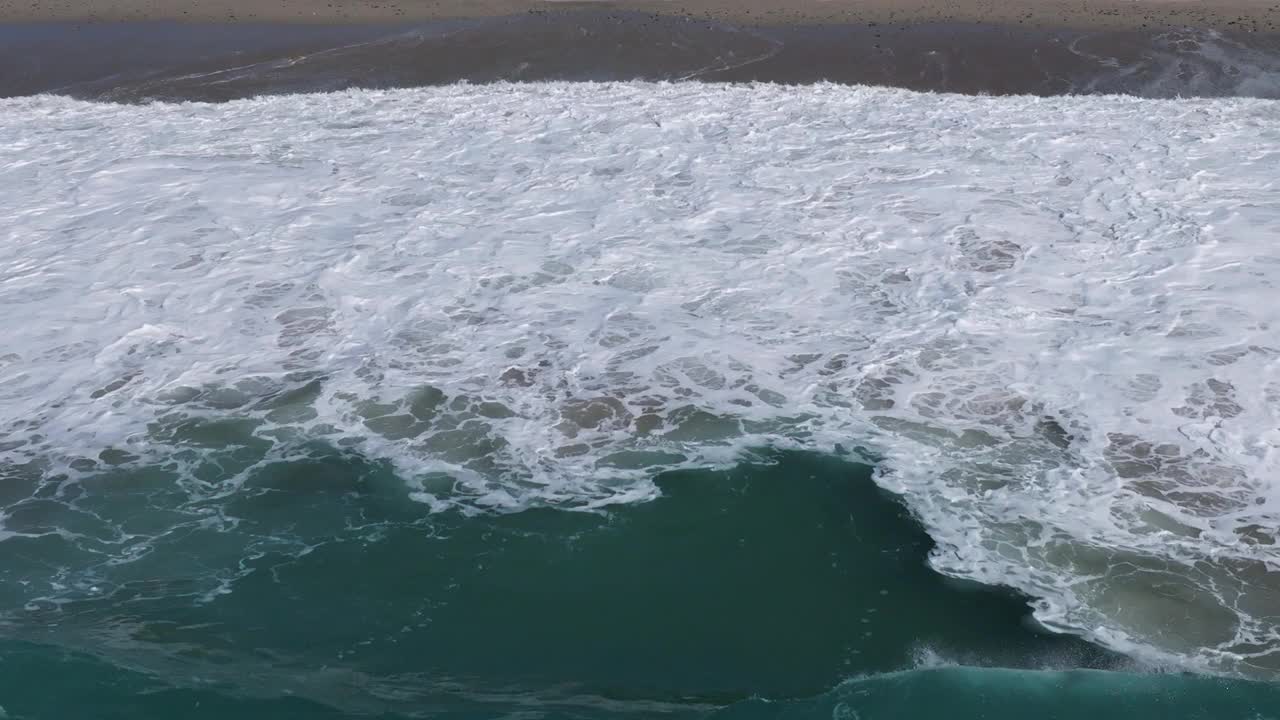 白色的海浪溅在海岸上的Playa Valcovo在阿特伊索，西班牙科鲁尼亚。空中，慢动作视频素材