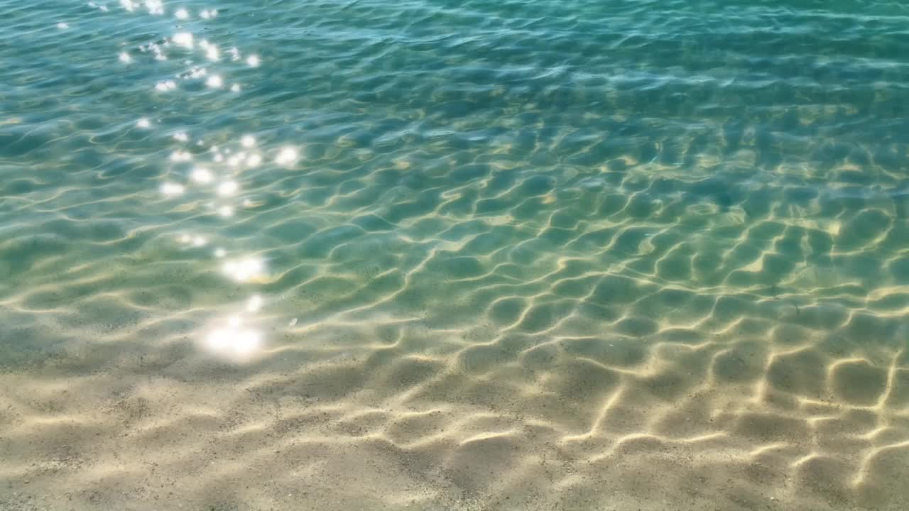 夏日沙滩上的蓝色波纹水面与阳光反射和闪闪发光的灯光的特写，海滩度假和旅游胜地的背景视频下载