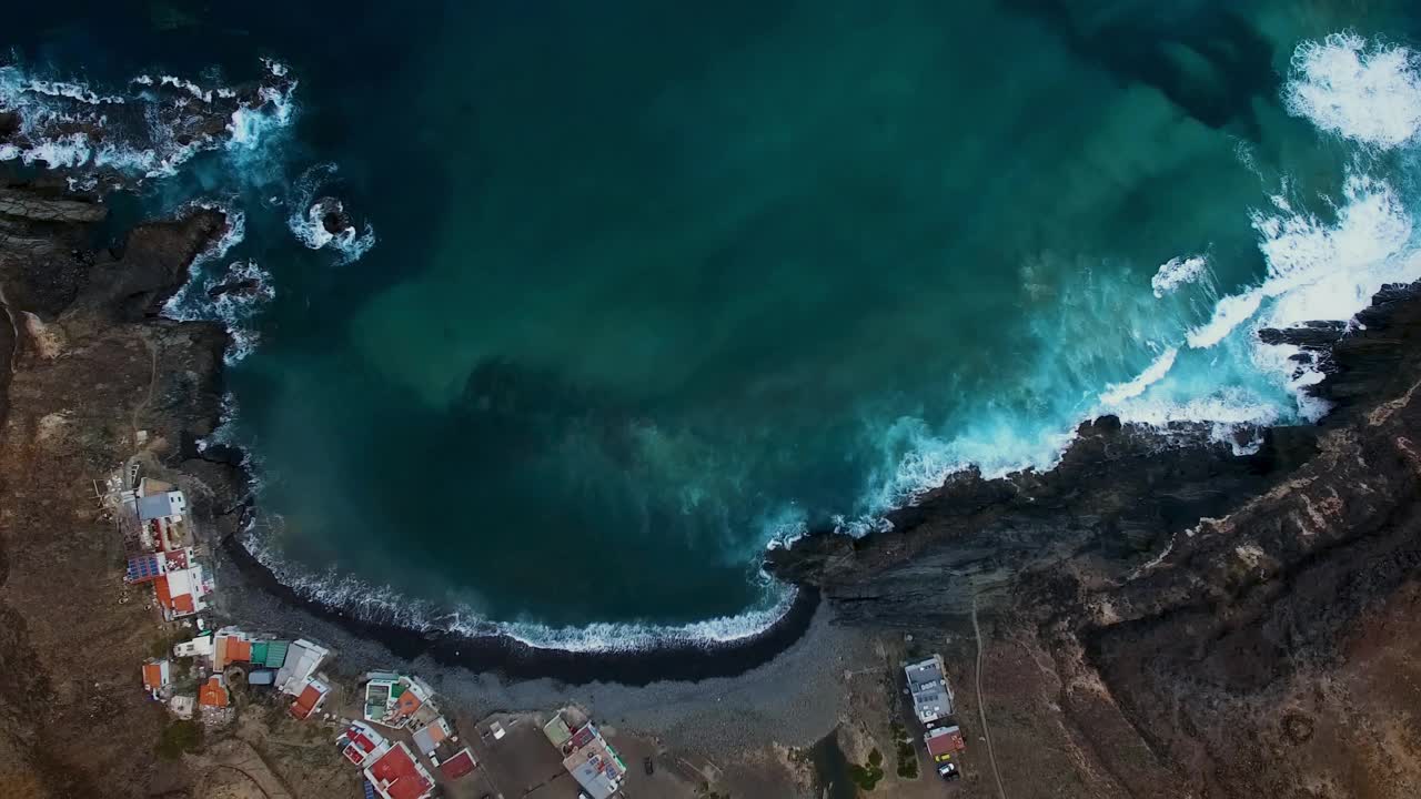 鸟瞰图展示了崎岖的海岸线，绿松石般的海水和附近的沿海村庄视频素材