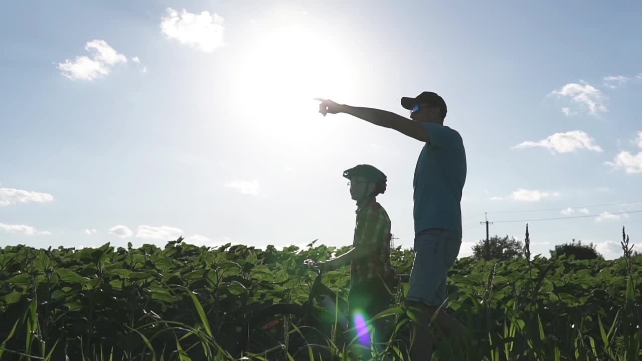 一个幸福的家庭。父亲在公园里教儿子骑自行车。视频下载