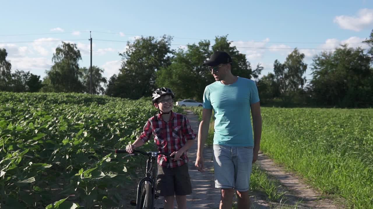 一个幸福的家庭。父亲在公园里教儿子骑自行车。视频素材