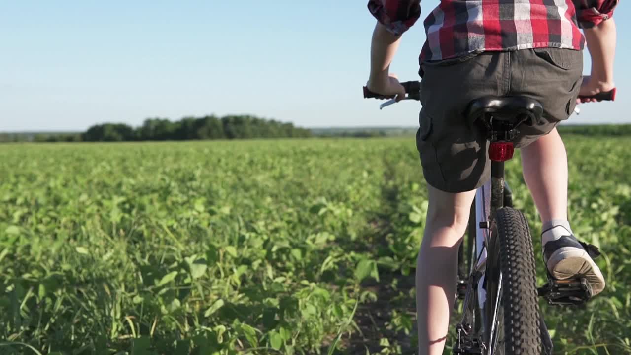 一个戴着头盔的男孩在公园里骑山地车。视频素材