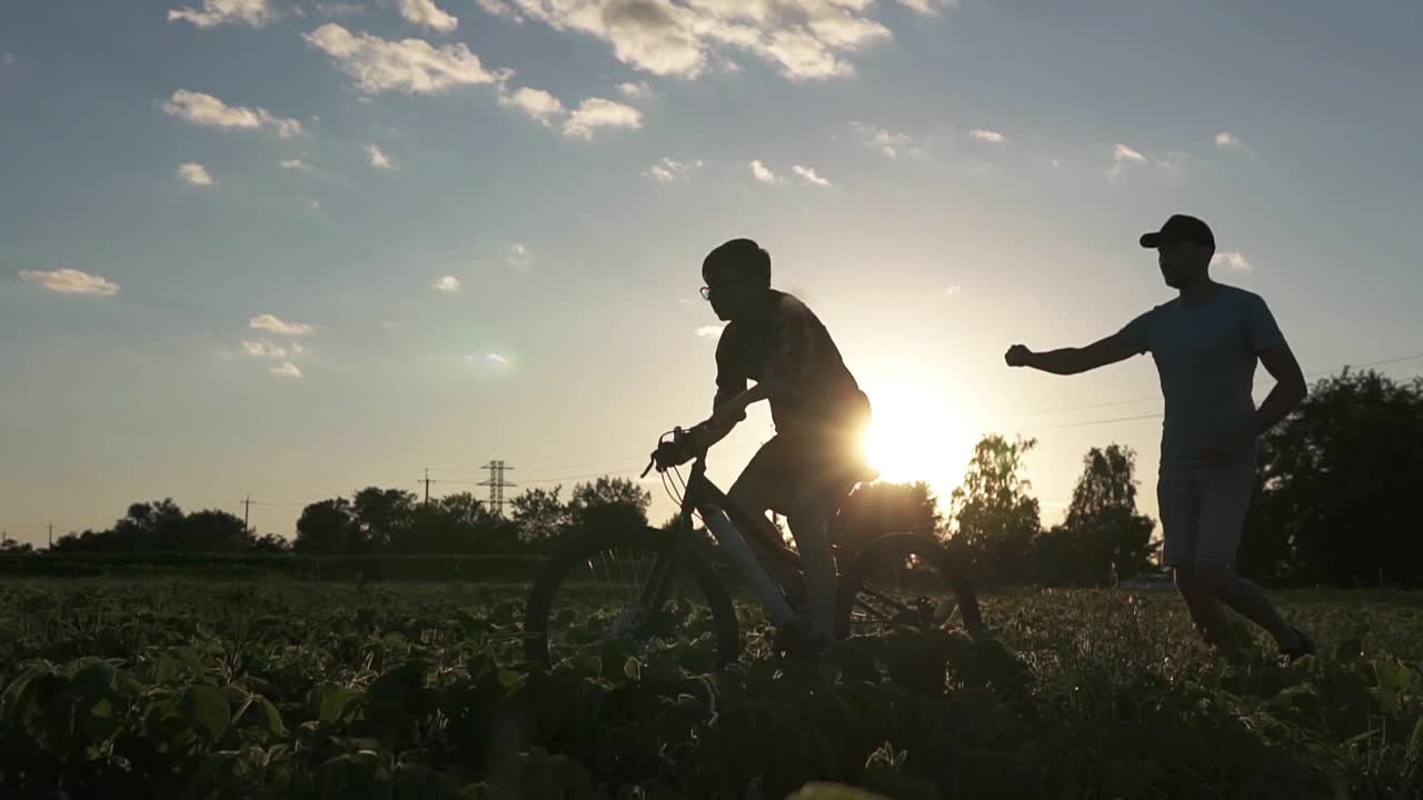 一个幸福的家庭。父亲在公园里教儿子骑自行车。视频素材