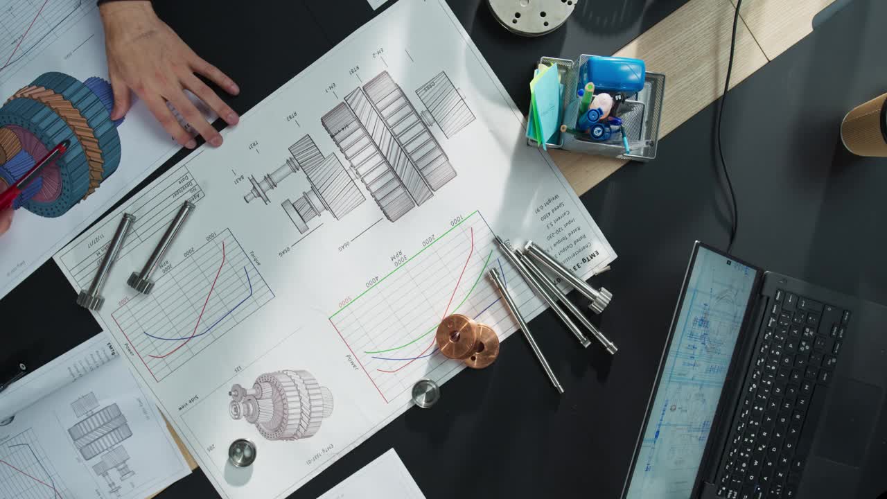 放大自顶向下的视图:不同的业务经理和建筑工程师团队在办公室里与重型工业机械的蓝图一起工作。同事用笔记本电脑、平板电脑进行团队合作视频素材