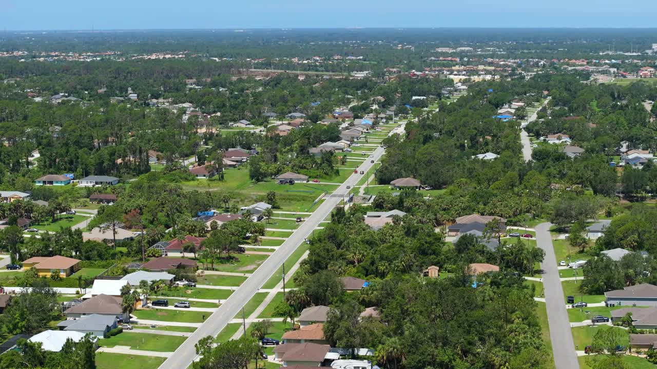 美国弗罗里达小镇的乡村公路上行驶着车辆。在安静的住宅区，绿树和郊区街道之间的私人住宅视频素材