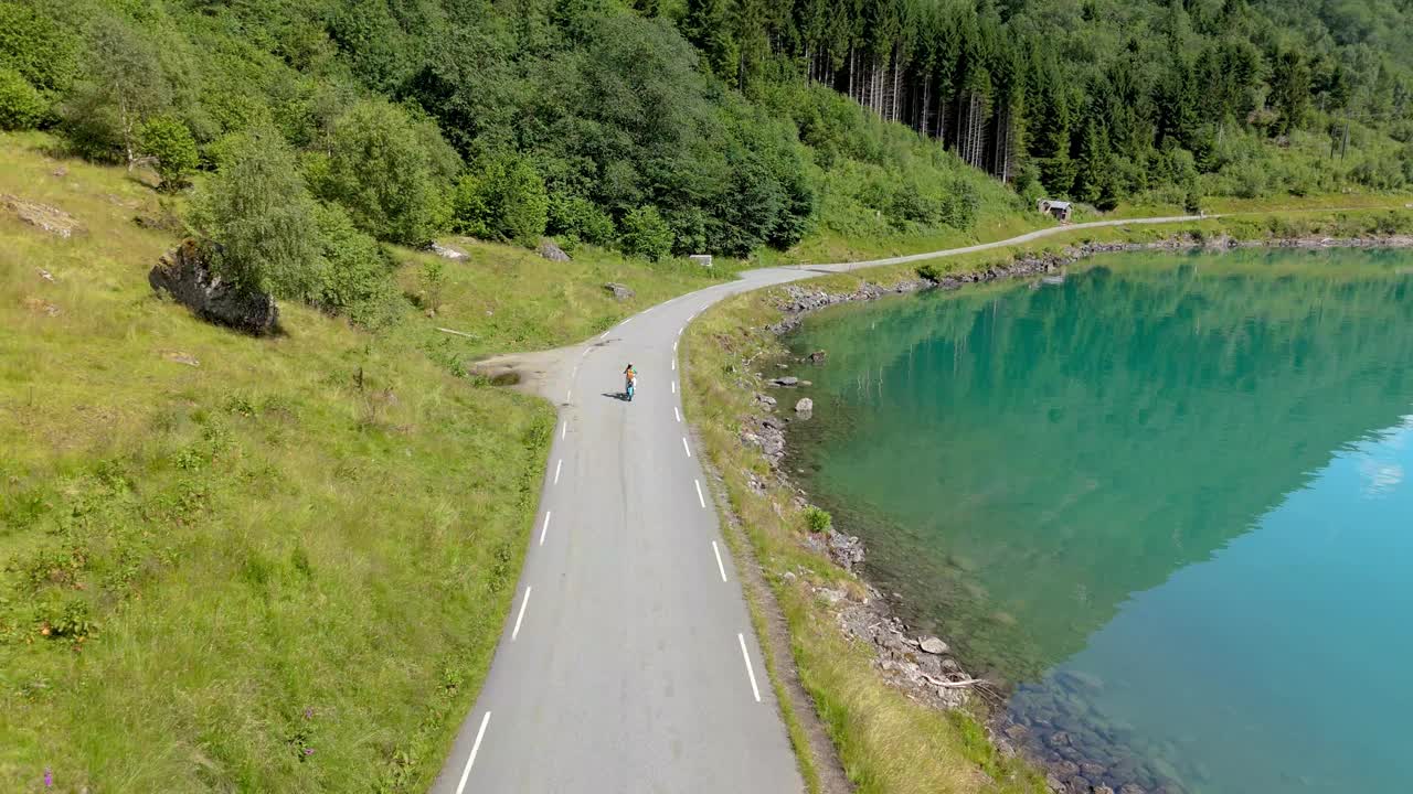 一个骑自行车的人骑在风景如画的湖边公路上，挪威的洛瓦内特视频素材