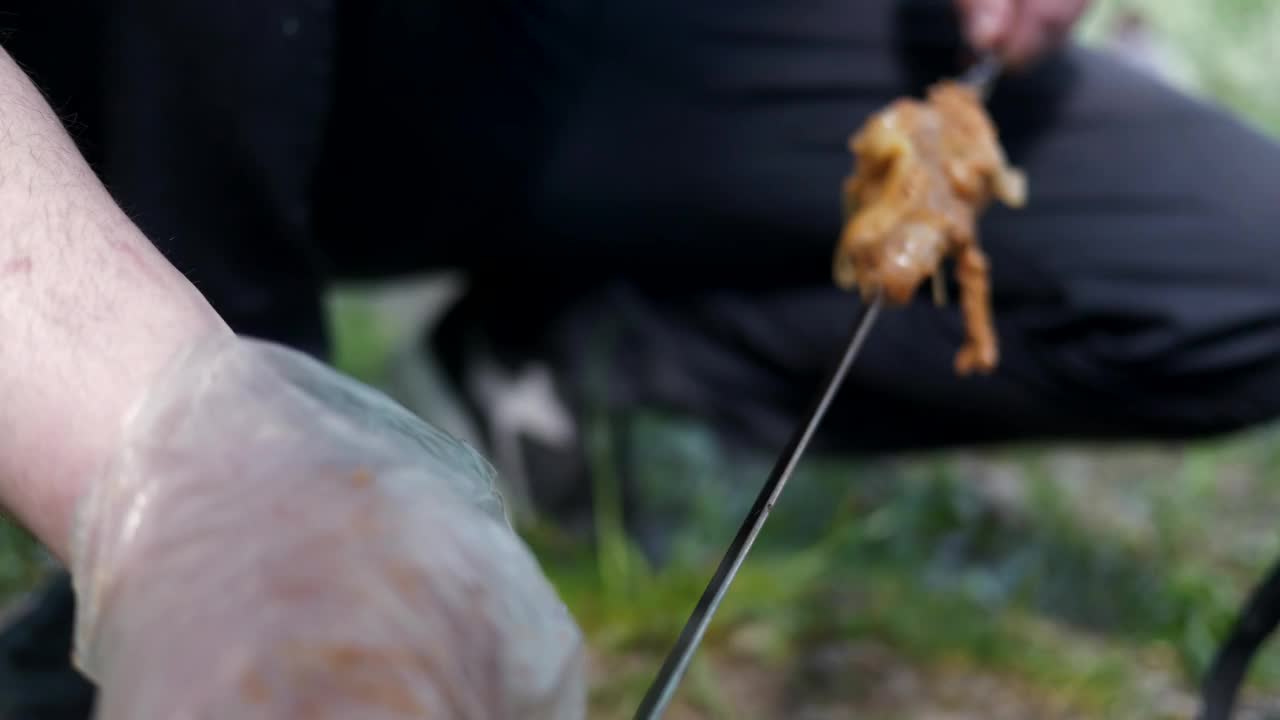 一个男人把腌过的肉串在烤肉串上的特写视频下载