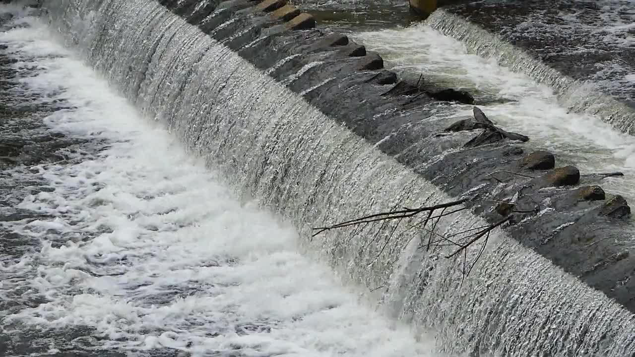 在雨季，大型水坝的大量水猛烈地冲击着岩石海岸。视频下载