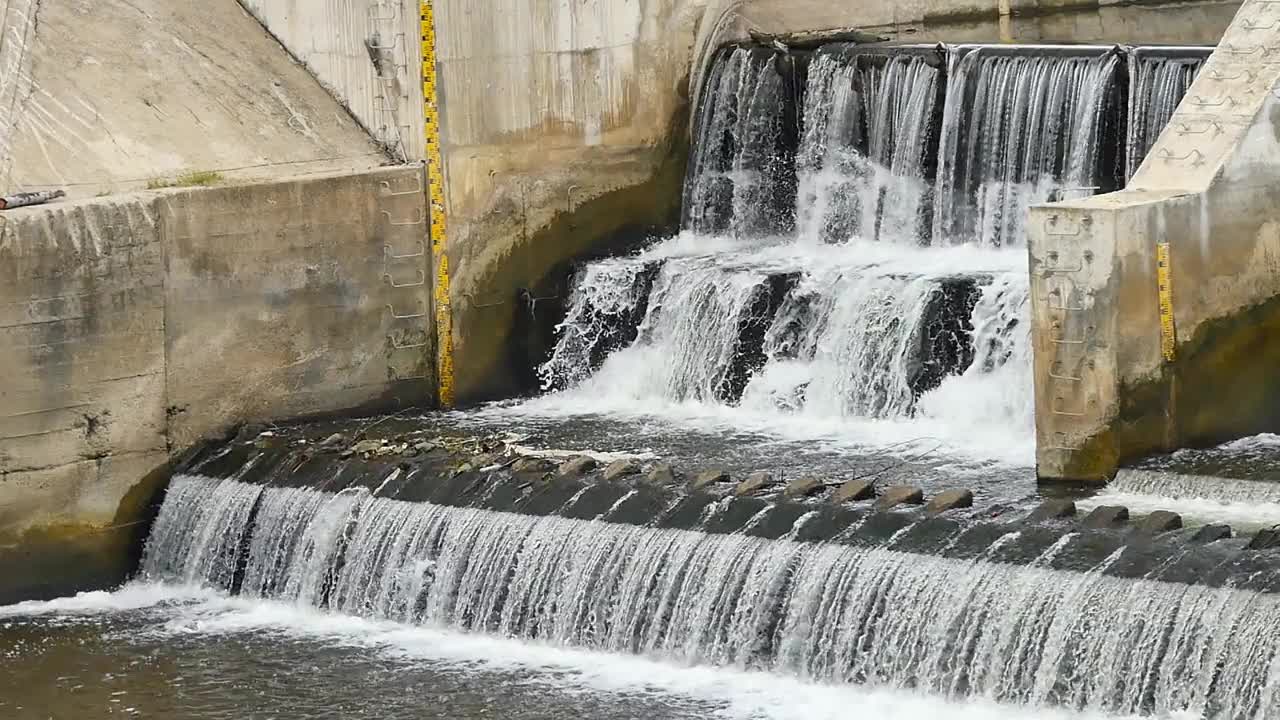 在雨季，大型水坝的大量水猛烈地冲击着岩石海岸。视频下载