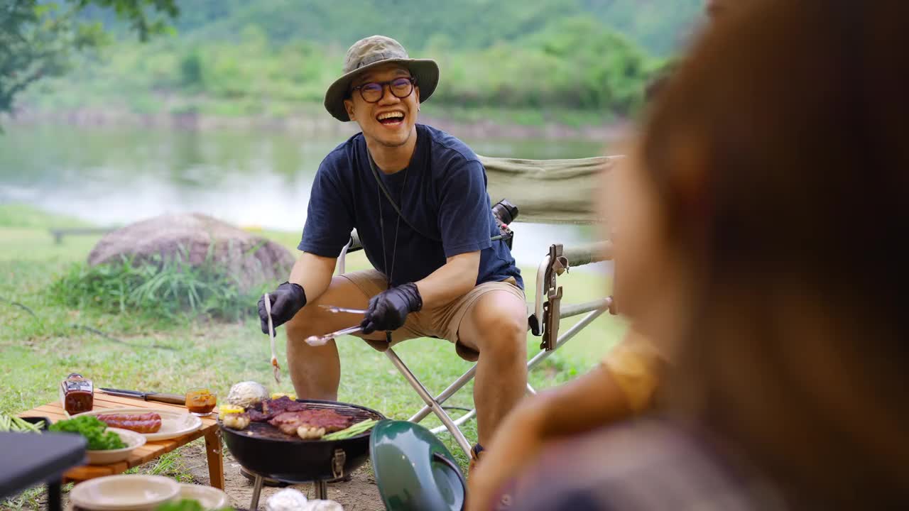 一群亚洲人晚上在森林里露营时一起吃晚餐。视频下载