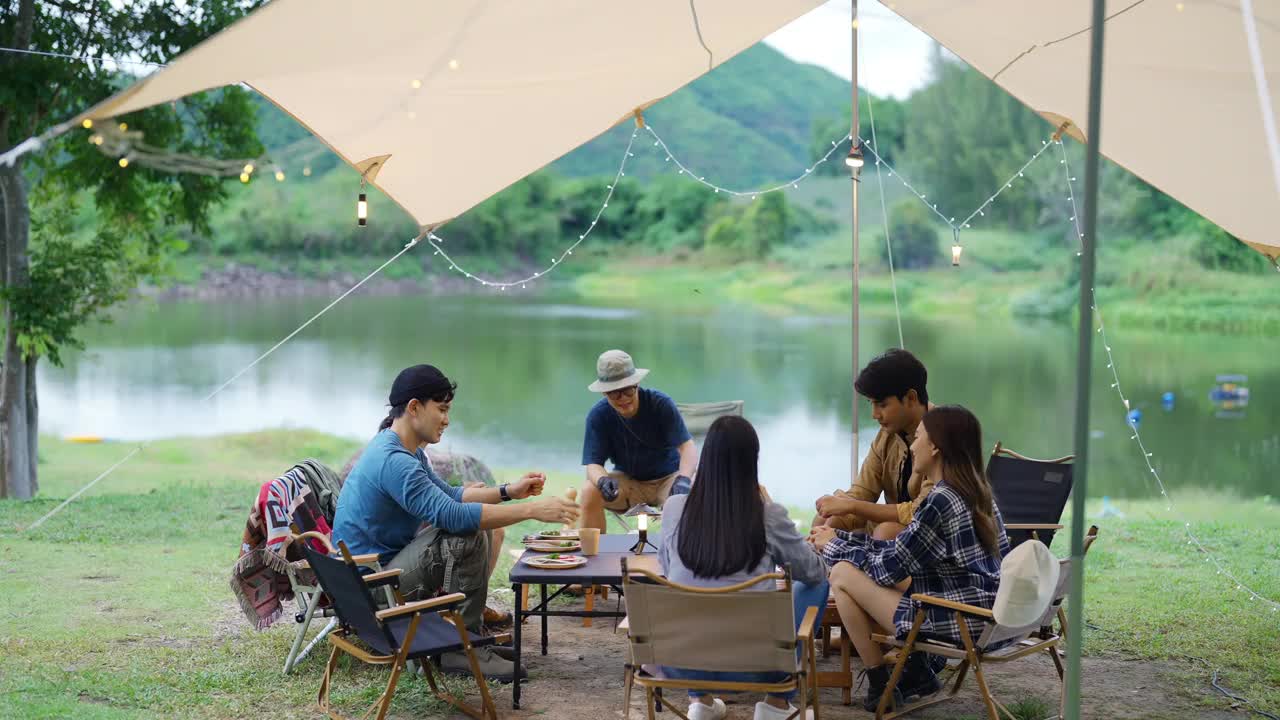 一群亚洲人晚上在森林里露营时一起吃晚餐。视频素材