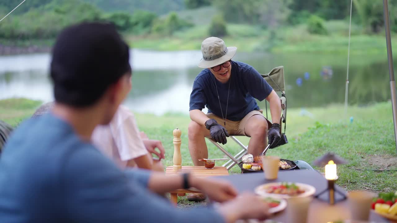 一群亚洲人晚上在森林里露营时一起吃晚餐。视频素材