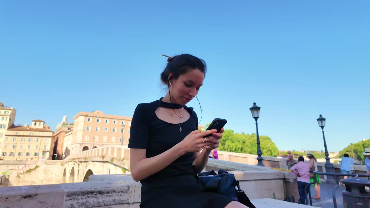 罗马的年轻女子在河边使用智能手机视频下载