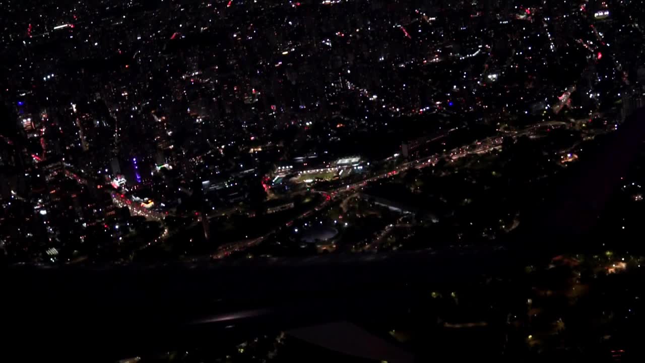 从飞机窗口看到夜晚城市的灯火辉煌。从机翼的窗户俯瞰夜晚的大都市。飞机起飞和爬升视频下载