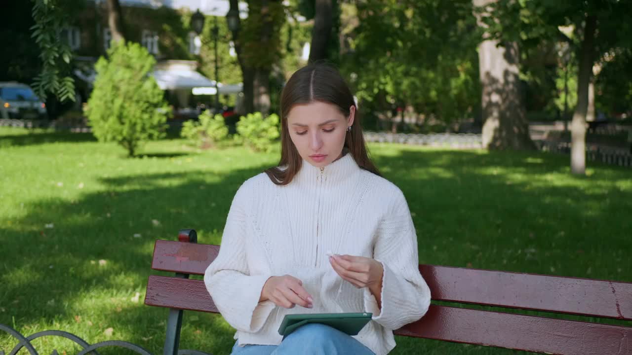 拿着平板电脑的女人在户外戴着耳机视频素材