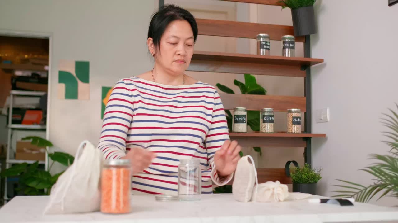 亚洲妇女用健康的有机谷物填充玻璃罐容器，用可持续的食品包装无塑料视频下载