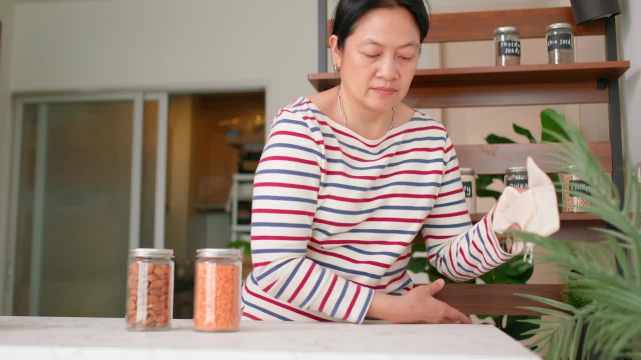 一名亚洲妇女在货架上摆放装有健康有机谷物超级食品的罐子视频素材