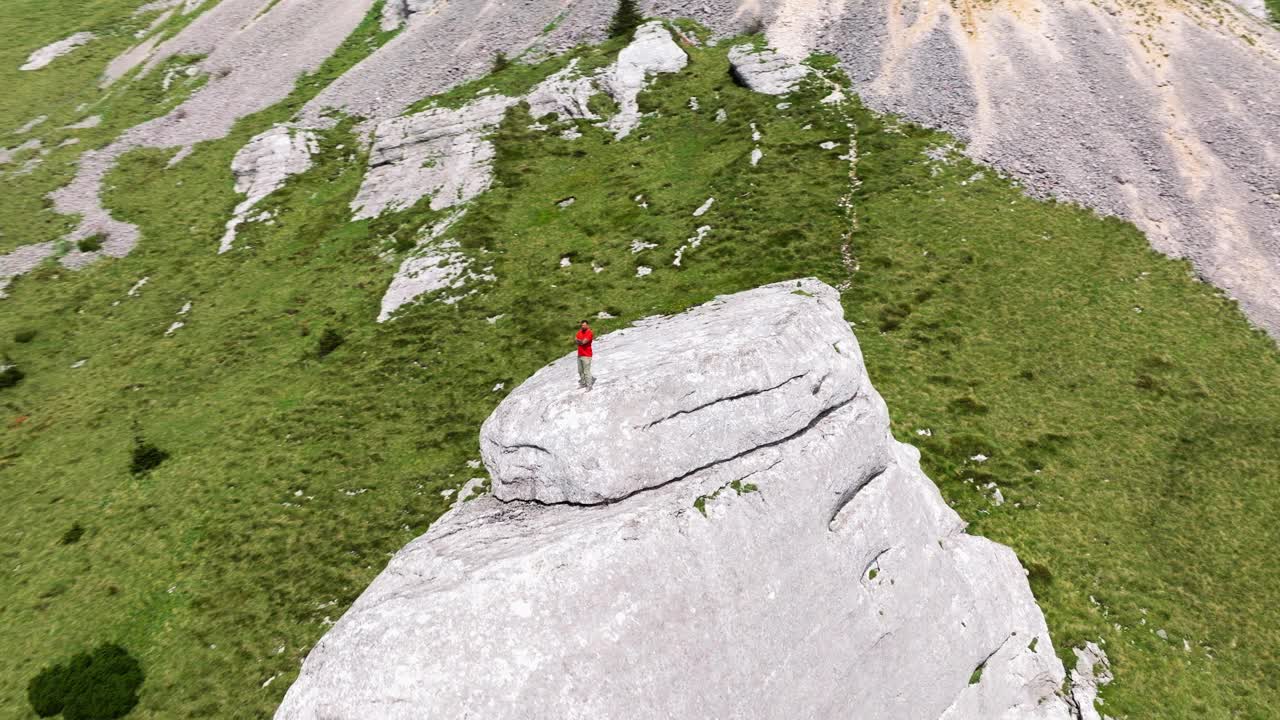 有冒险精神的徒步旅行者站在陡峭山坡上的岩层上。克罗地亚的Pljesivica山。无人机回射视频素材