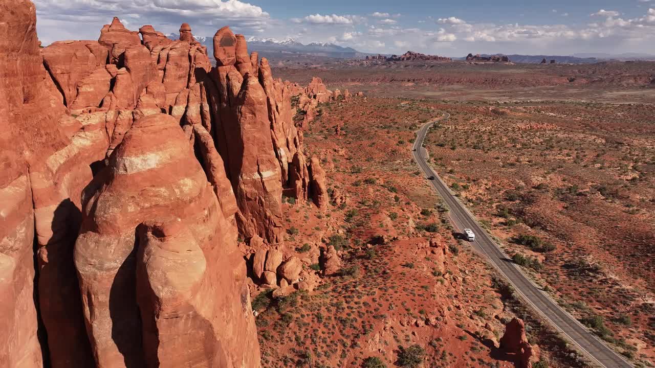 红色的岩层沿着蜿蜒的道路上升，穿过美国犹他州摩押的广阔沙漠景观视频素材