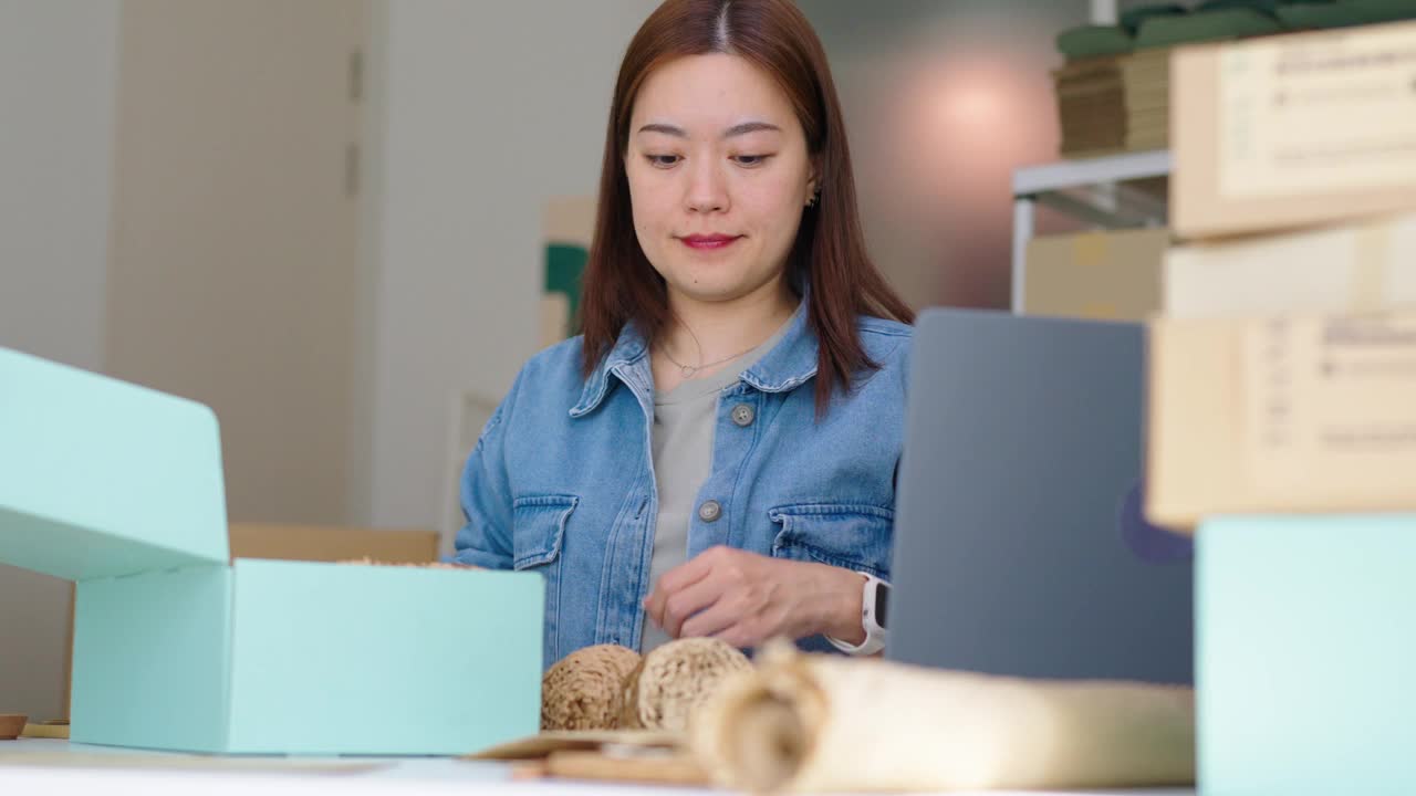 聪明的年轻亚洲企业家企业家女老板包装和标签的环保牛皮纸蜂窝包裹环境可持续发展的纸张可生物降解材料，然后运送给客户，零浪费和无塑料的概念视频素材