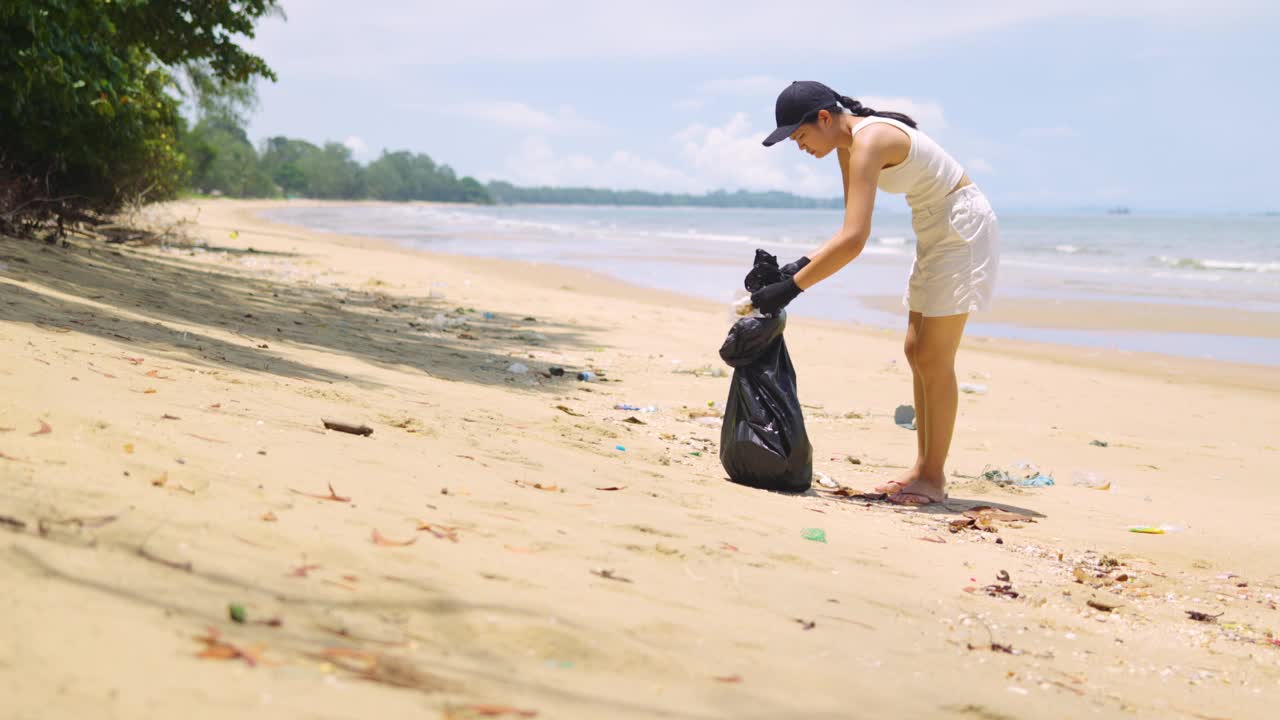 志愿者沿着海滩散步和收集垃圾。视频素材